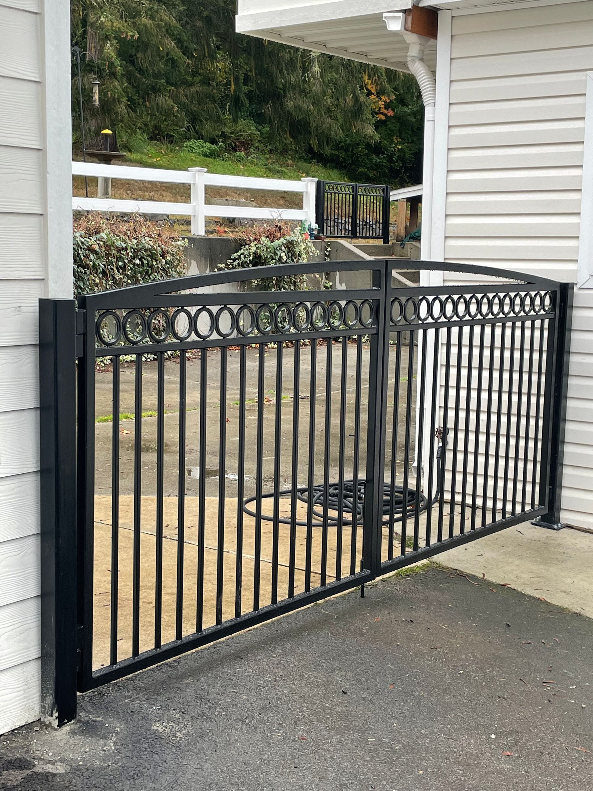 A black gate is sitting in front of a white house
