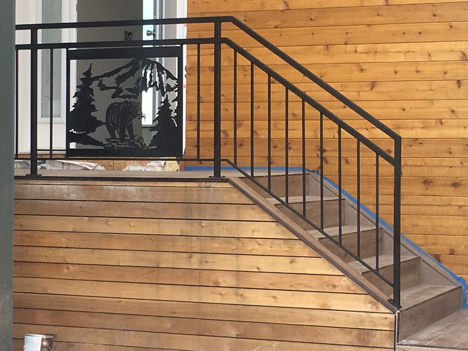 A wooden staircase with a metal railing and a bear on it