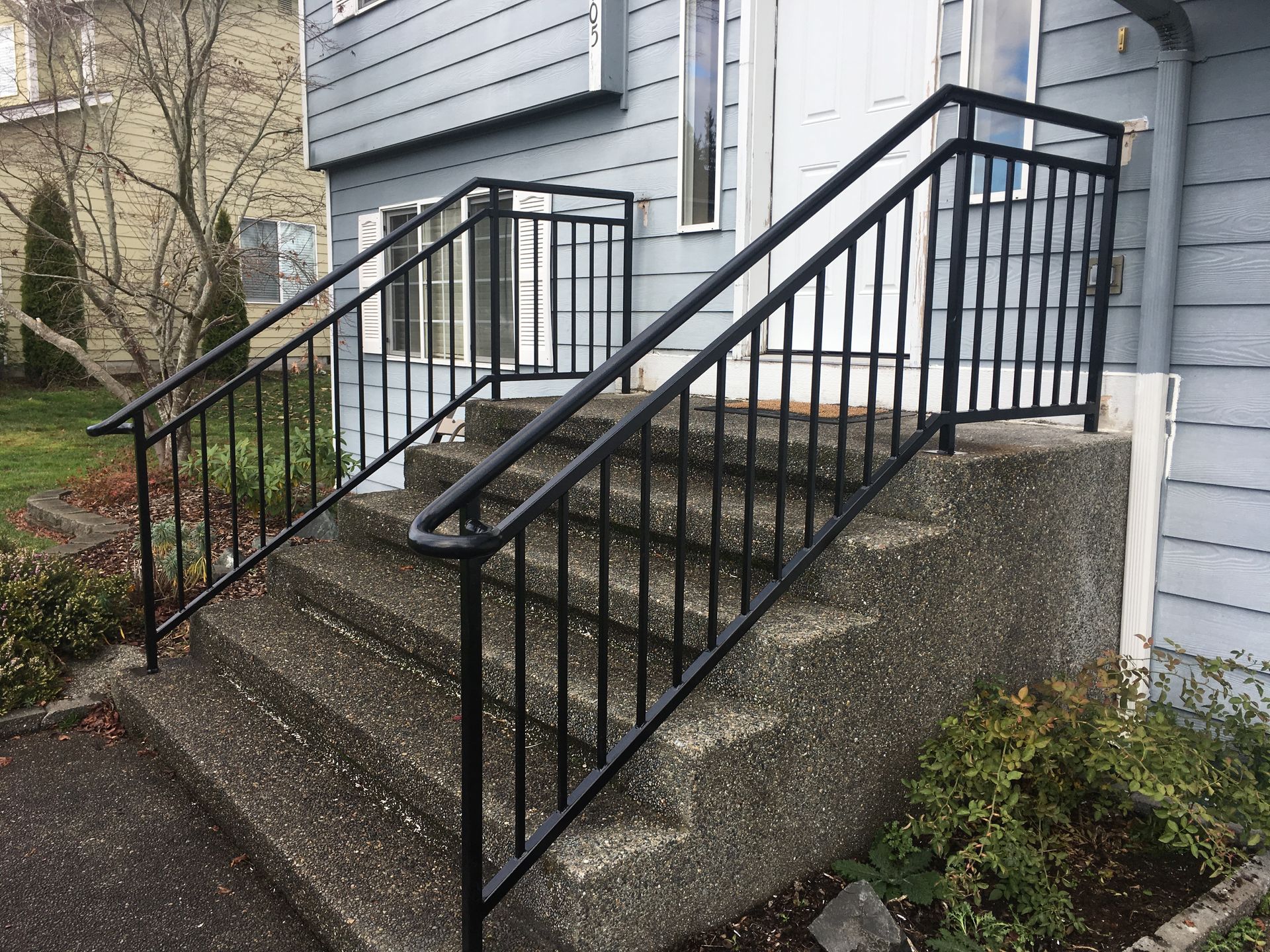 A staircase with a black railing leading up to a house