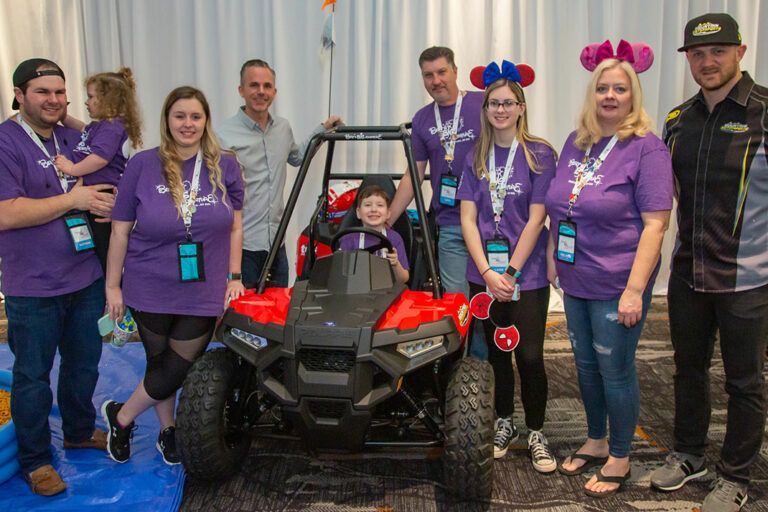 A group of people are posing for a picture in front of a toy atv.