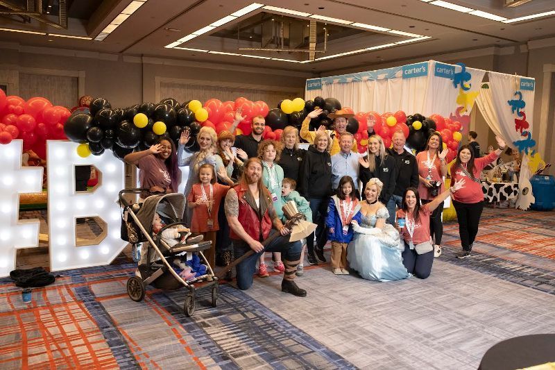 A group of people are posing for a picture in a room with balloons.