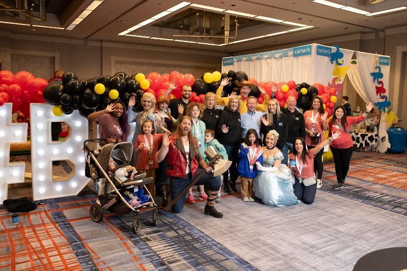 A group of people are posing for a picture in a room with balloons.