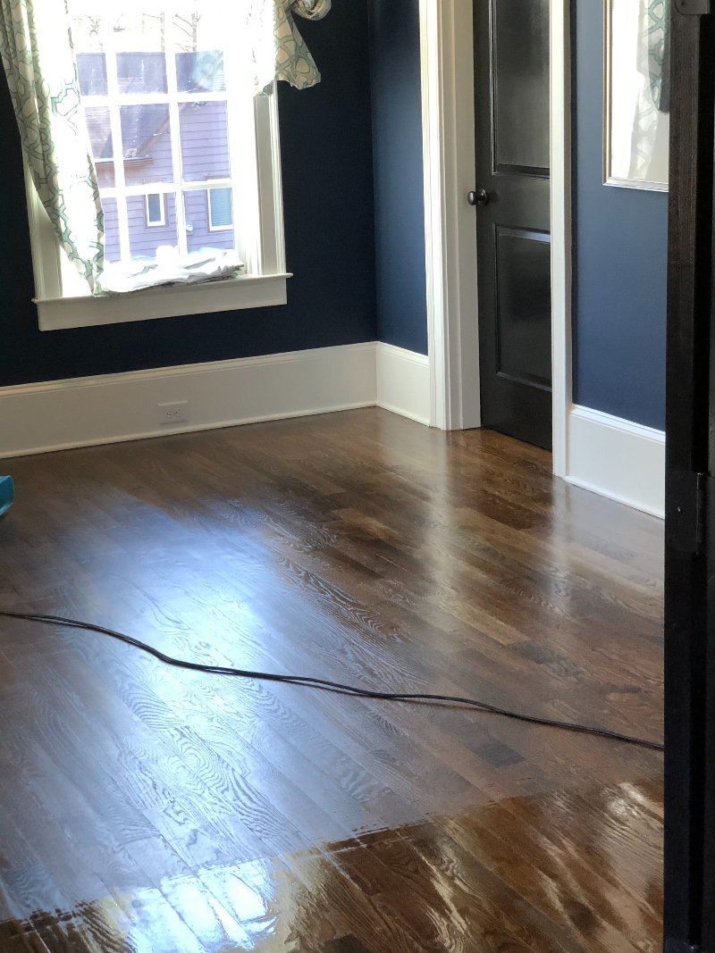 A room with hardwood floors , blue walls and a window.