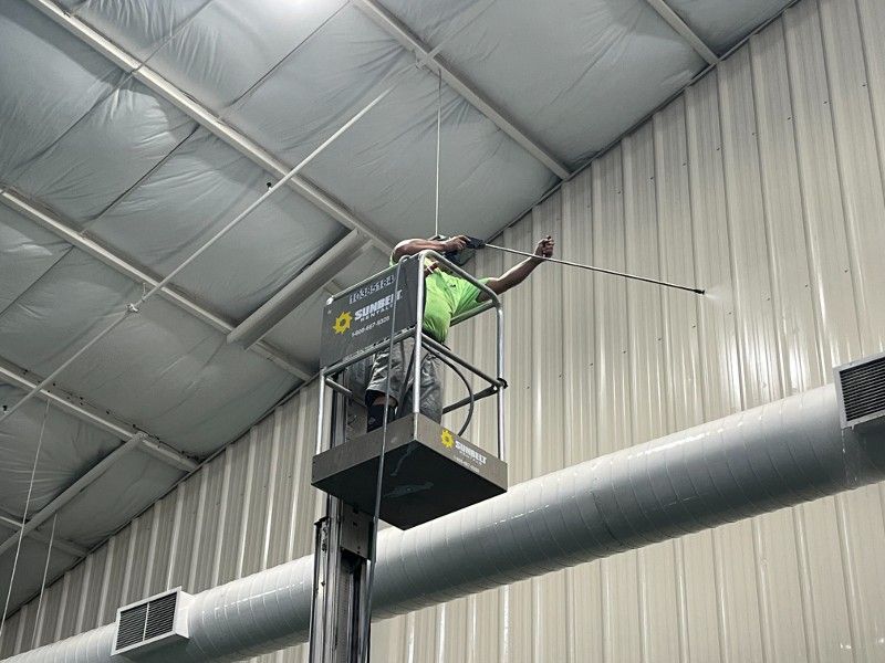 A man is cleaning the ceiling of a building with a hose.