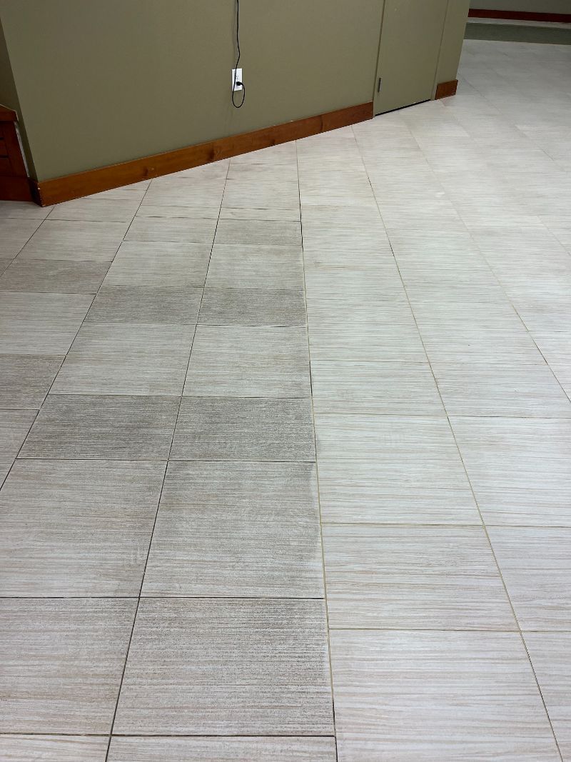 A tiled floor in a room with a few spots of dirt on it.