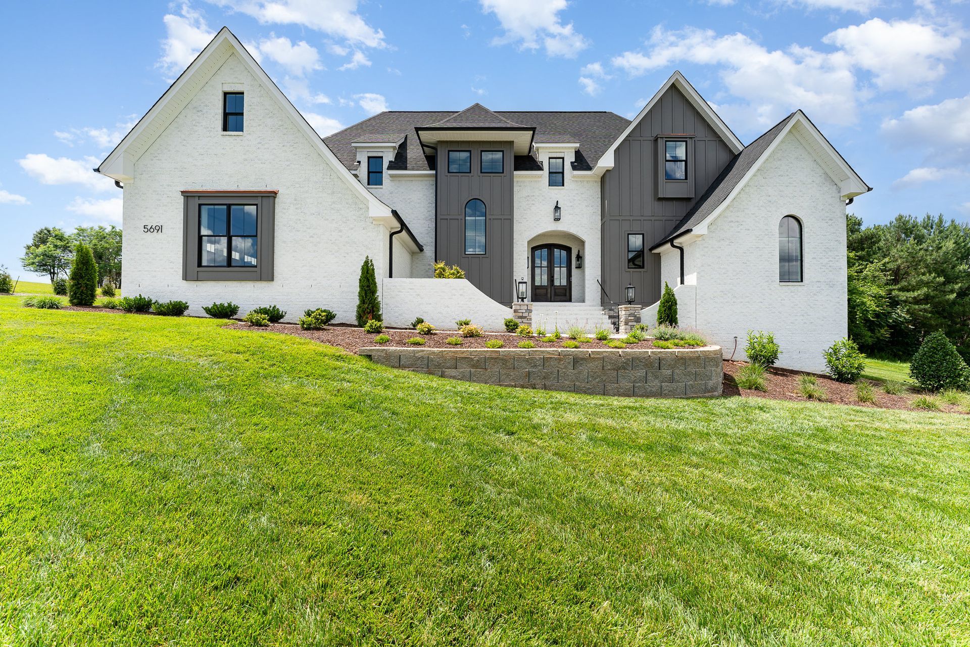 A large white house is sitting on top of a lush green hill.