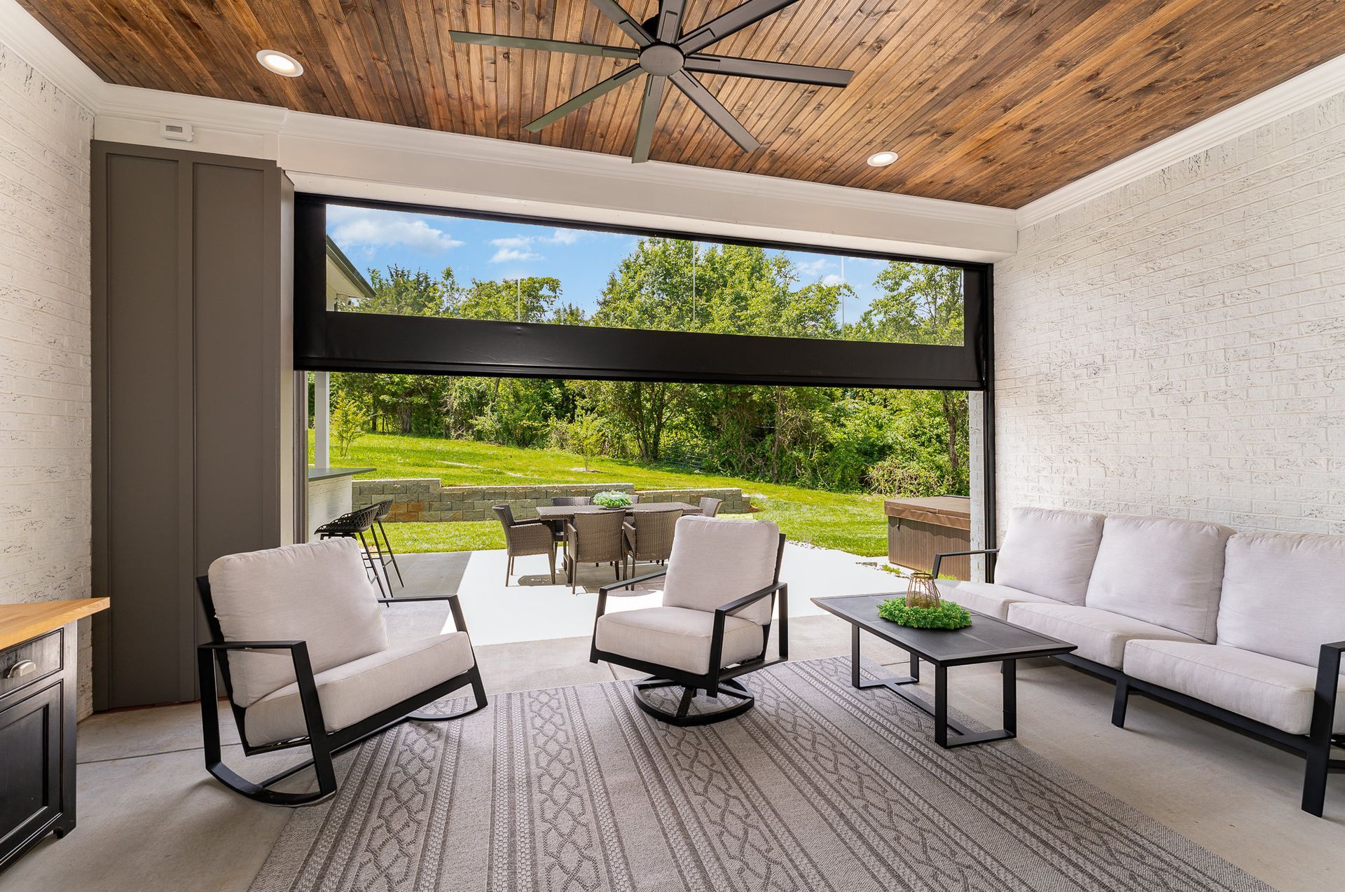 A living room with a couch, chairs, a table, and a ceiling fan.