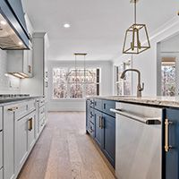 A kitchen with white cabinets and blue cabinets and a stainless steel dishwasher.