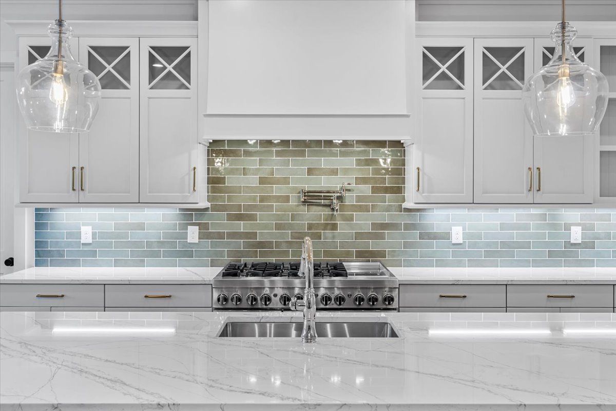 Modern kitchen with white cabinets, stainless steel appliances, and a gray-tiled backsplash.