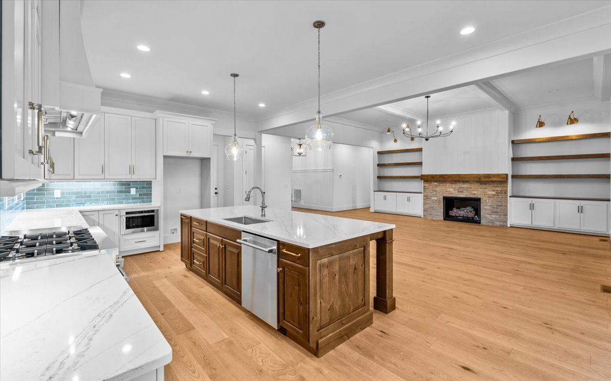 Spacious kitchen with wood island, white cabinets, and a living area with a fireplace and bookshelves.