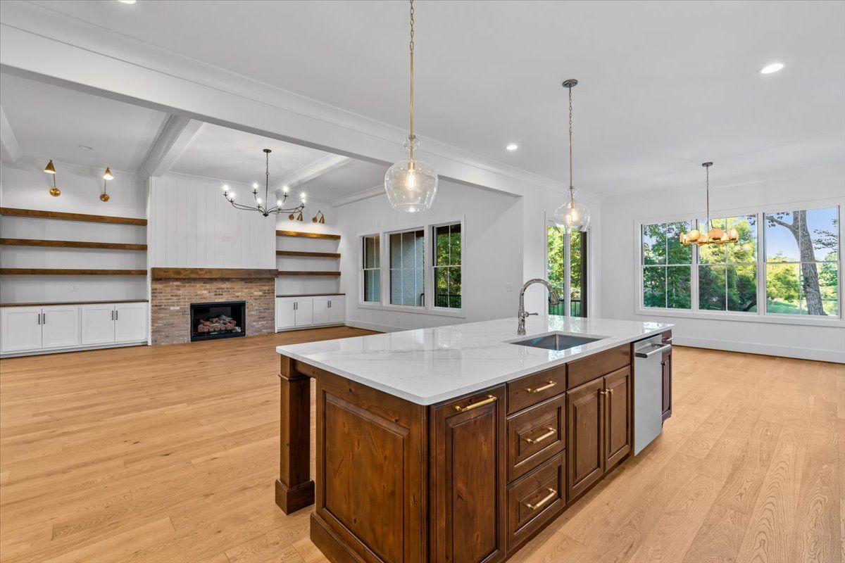 Kitchen with wooden island, white countertops, stainless steel appliances, and large windows.