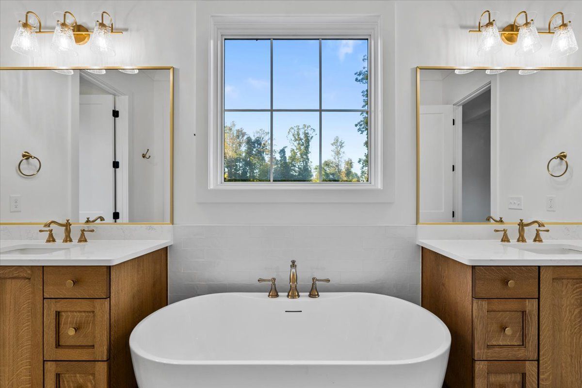 Bathroom with a freestanding tub, dual vanities, and a window with a view.