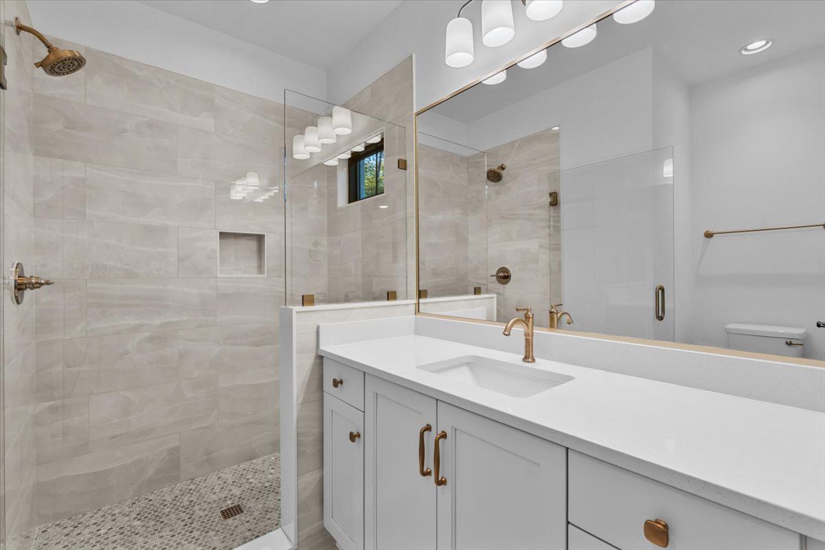 Modern bathroom with white vanity, large mirror, and glass shower.