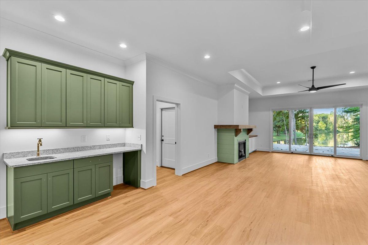 Empty room with sage green cabinets, fireplace, and sliding glass doors. Hardwood floors.