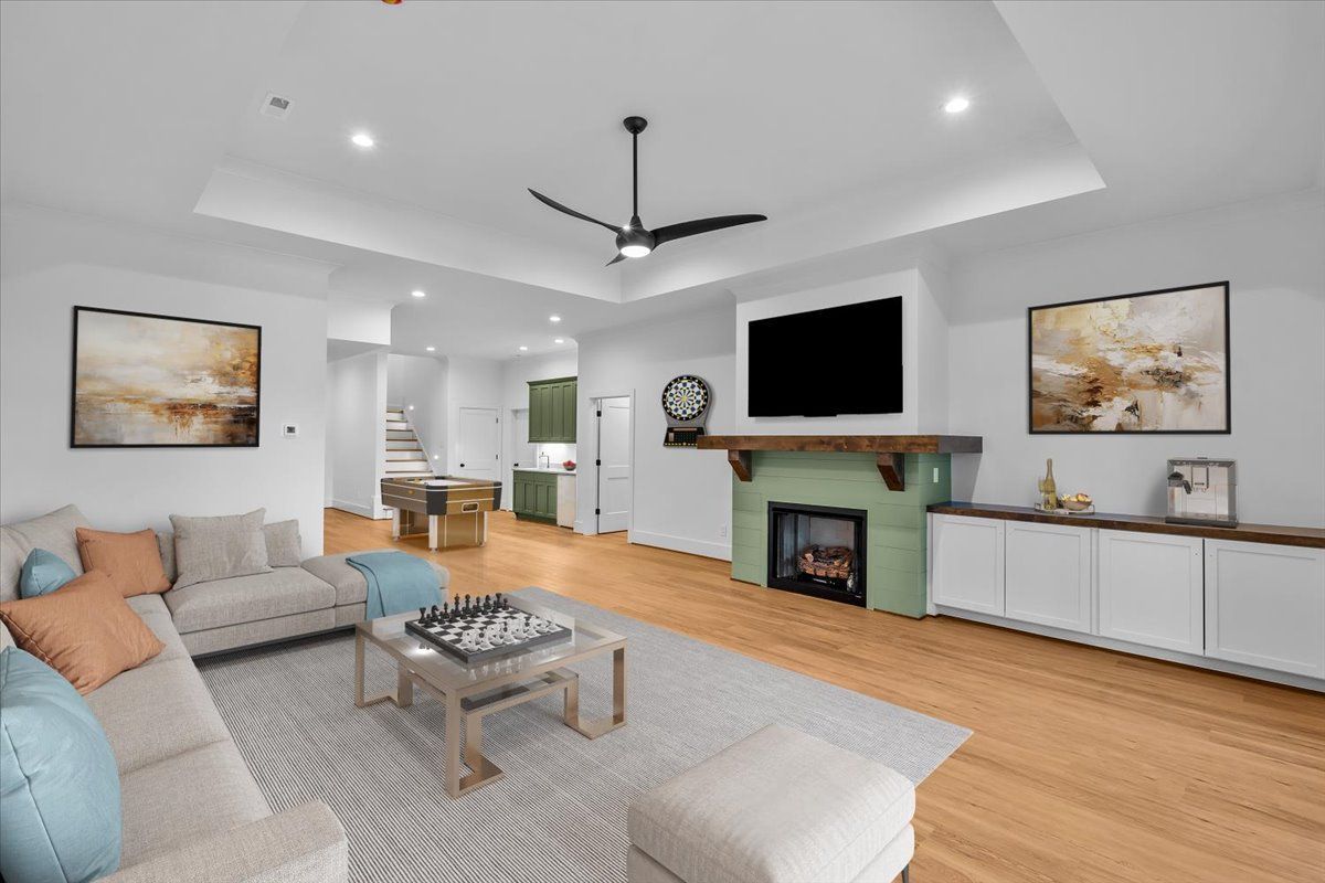 Spacious living room with fireplace, TV, sectional sofa, art, and light wood floors.