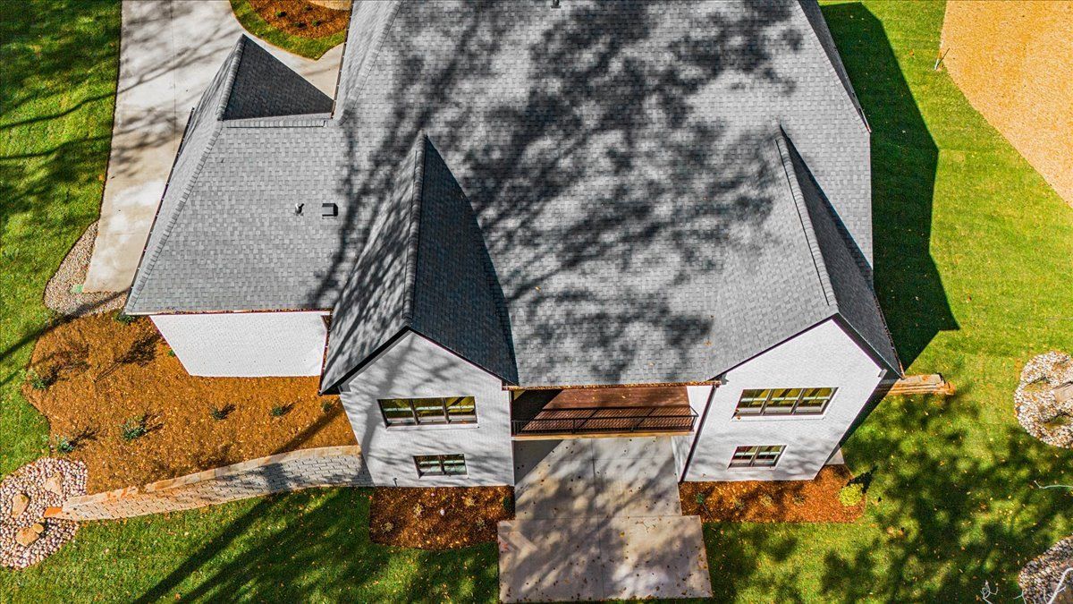 Overhead view of a modern house with gray roof, white walls, and landscaped yard.