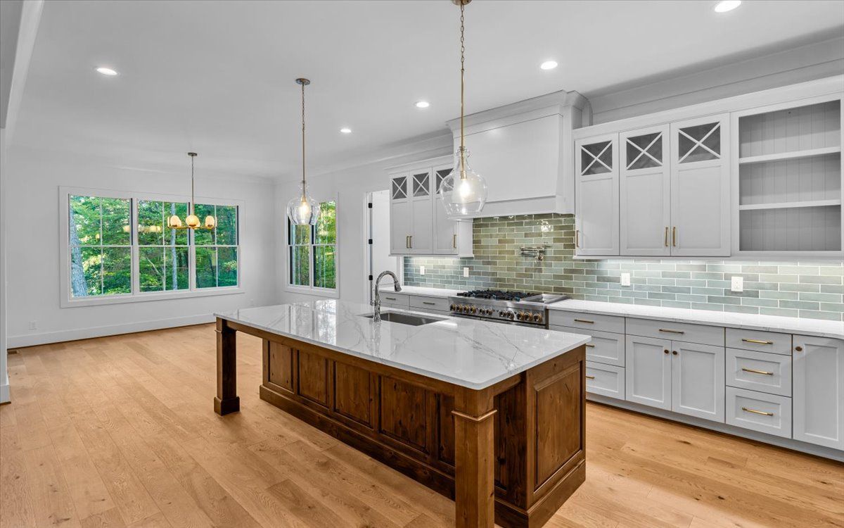 Spacious kitchen with wood flooring, white cabinetry, a large island, and natural light from windows.