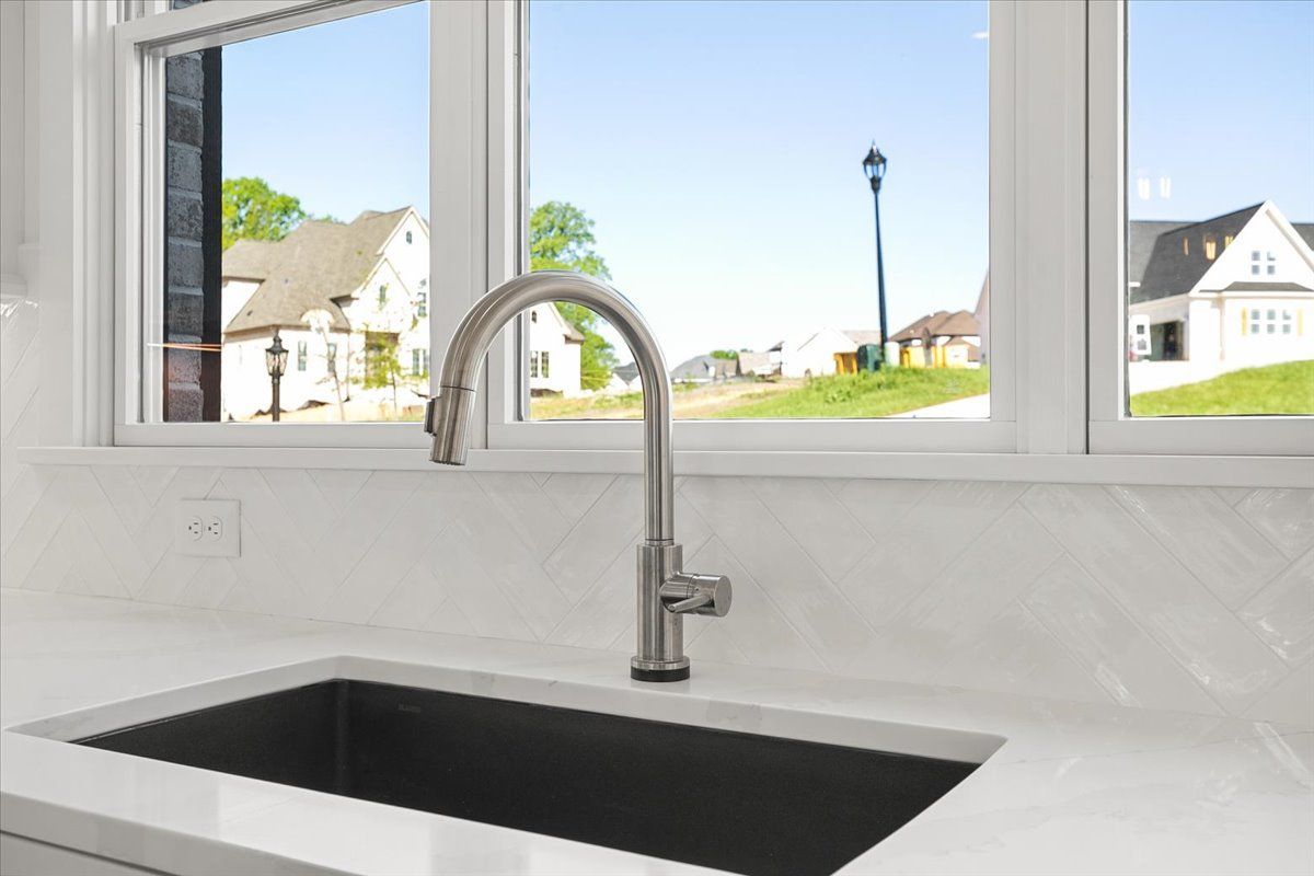 A kitchen sink with a faucet and a window in the background