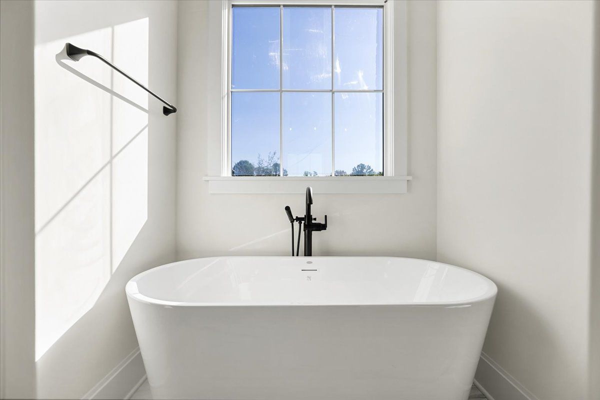 A white bathtub in a bathroom next to a window