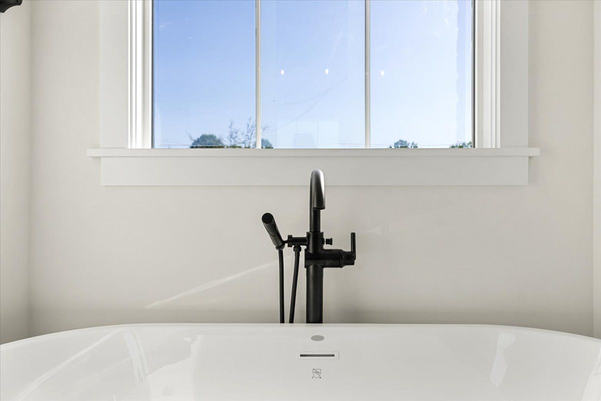 A white bathtub with a black faucet