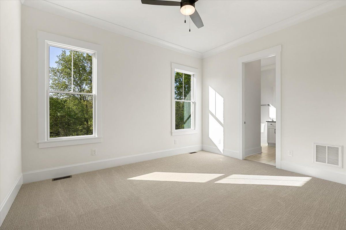 An empty bedroom with a ceiling fan and two windows