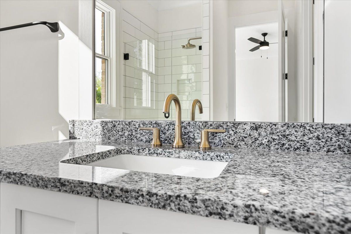 A bathroom with a granite counter top and a sink