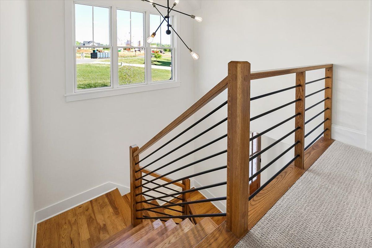 A wooden staircase with a metal railing and a window