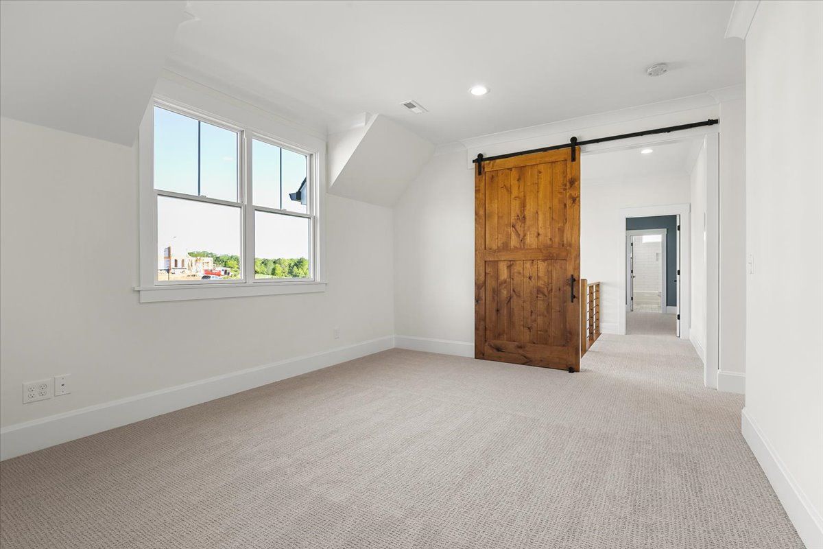 An empty room with a sliding barn door and a window