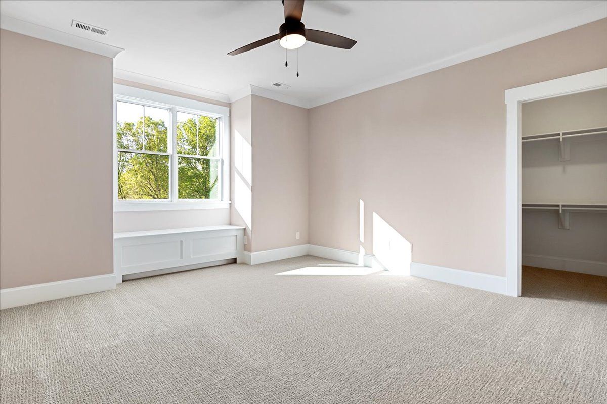 An empty bedroom with a ceiling fan and a walk-in closet