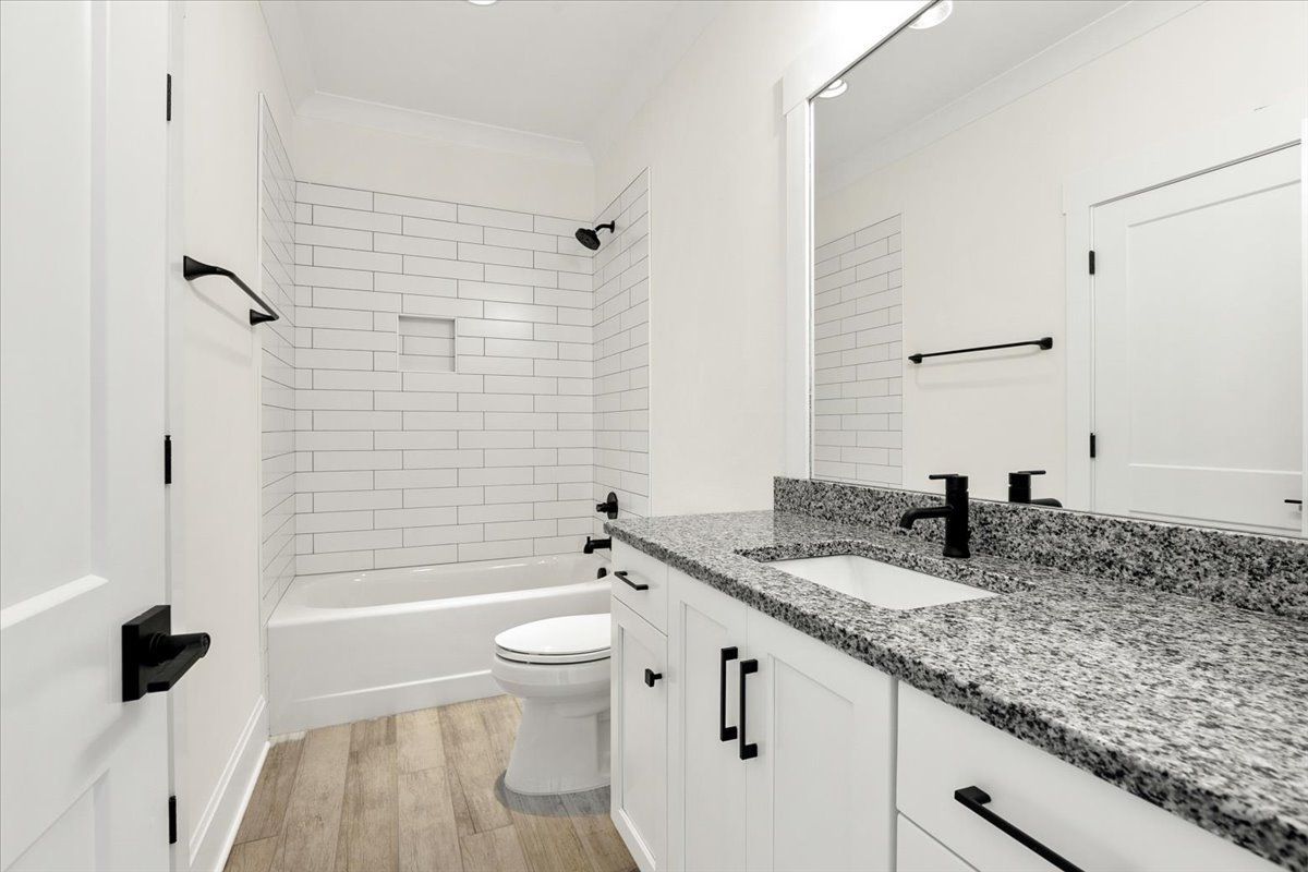 Bathroom with white wall tiles, wooden floor, and marble countertop