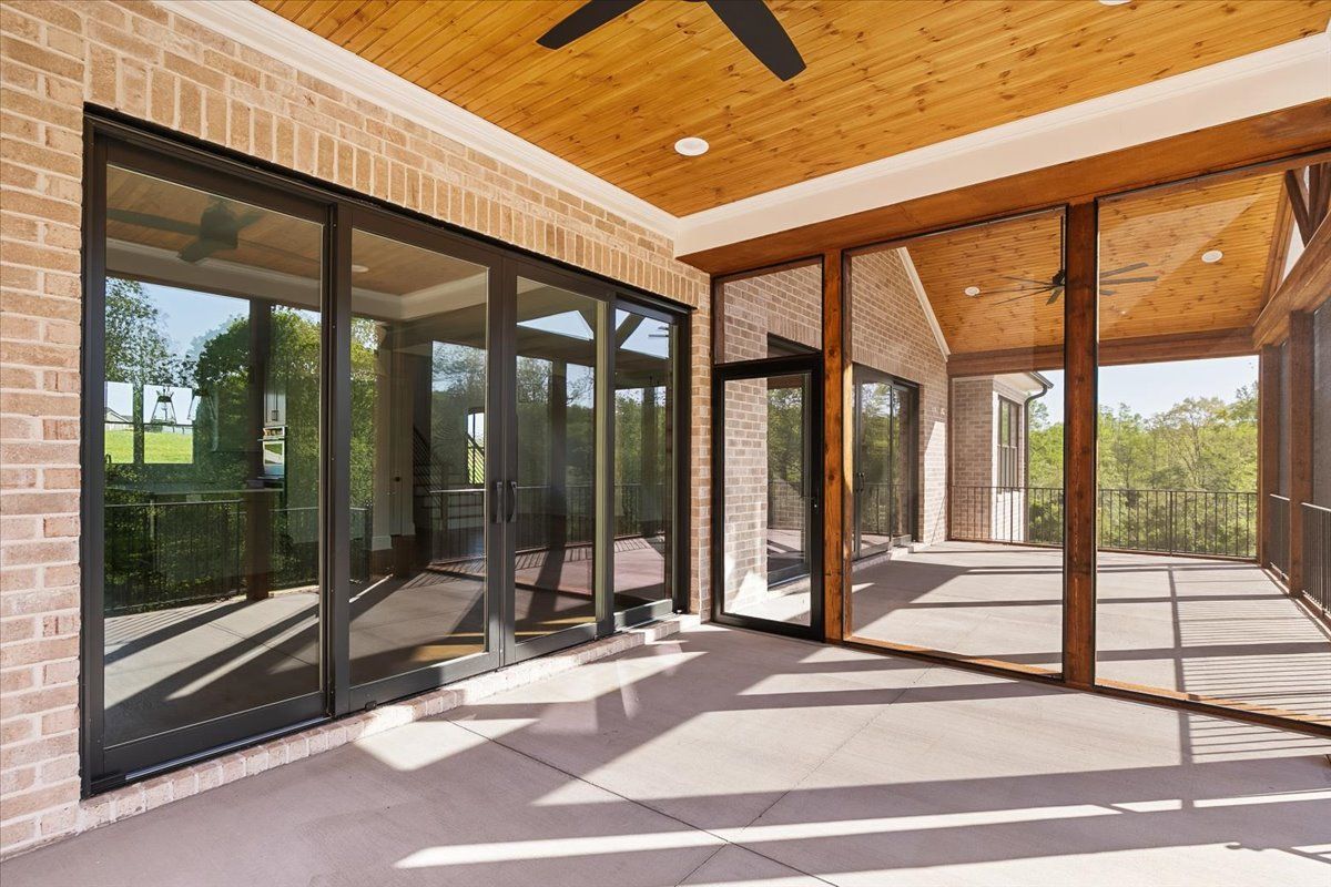 A screened-in porch with lots of windows and a ceiling fan