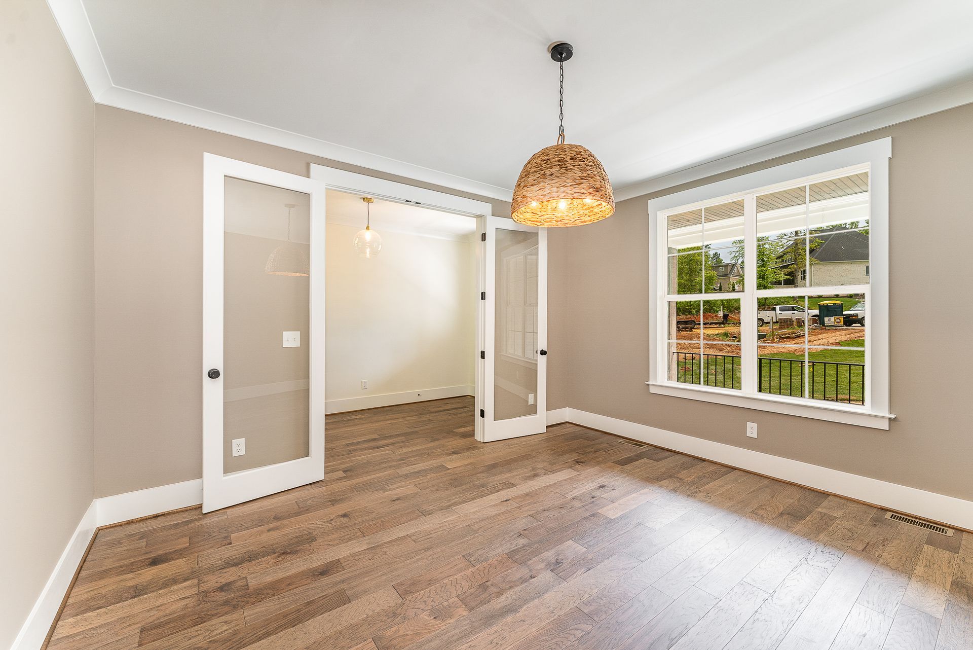 An empty room with hardwood floors and a chandelier