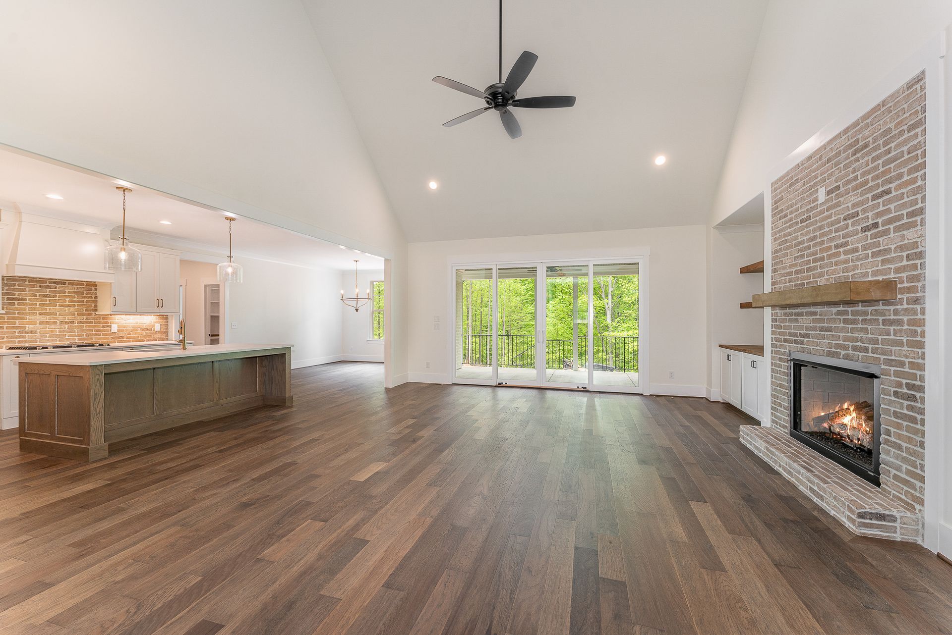 A living room with hardwood floors, a fireplace, and a ceiling fan