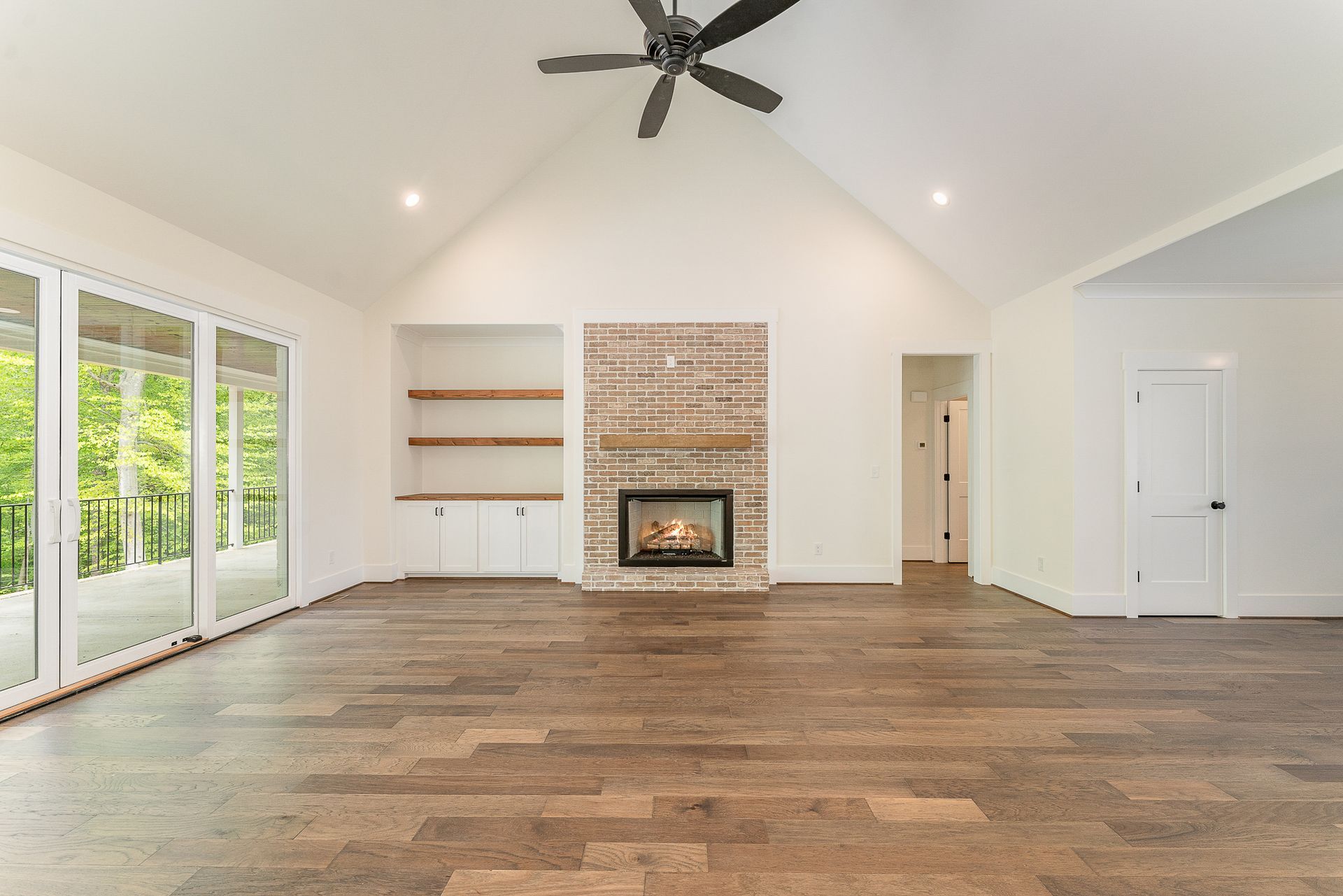 An empty living room with a fireplace and a ceiling fan
