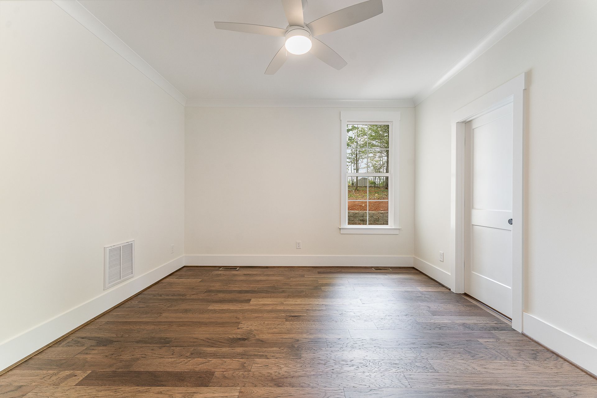 An empty room with a ceiling fan and a window