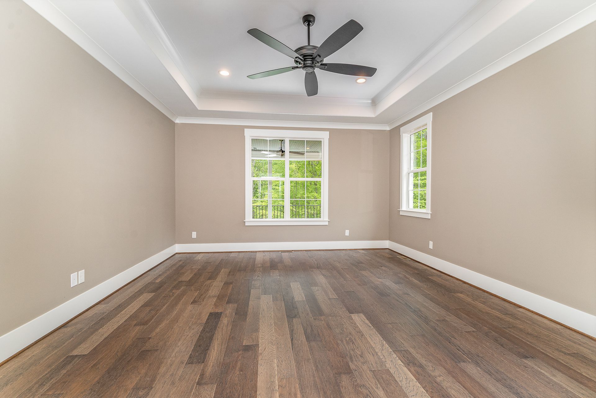 An empty room with two windows and a ceiling fan