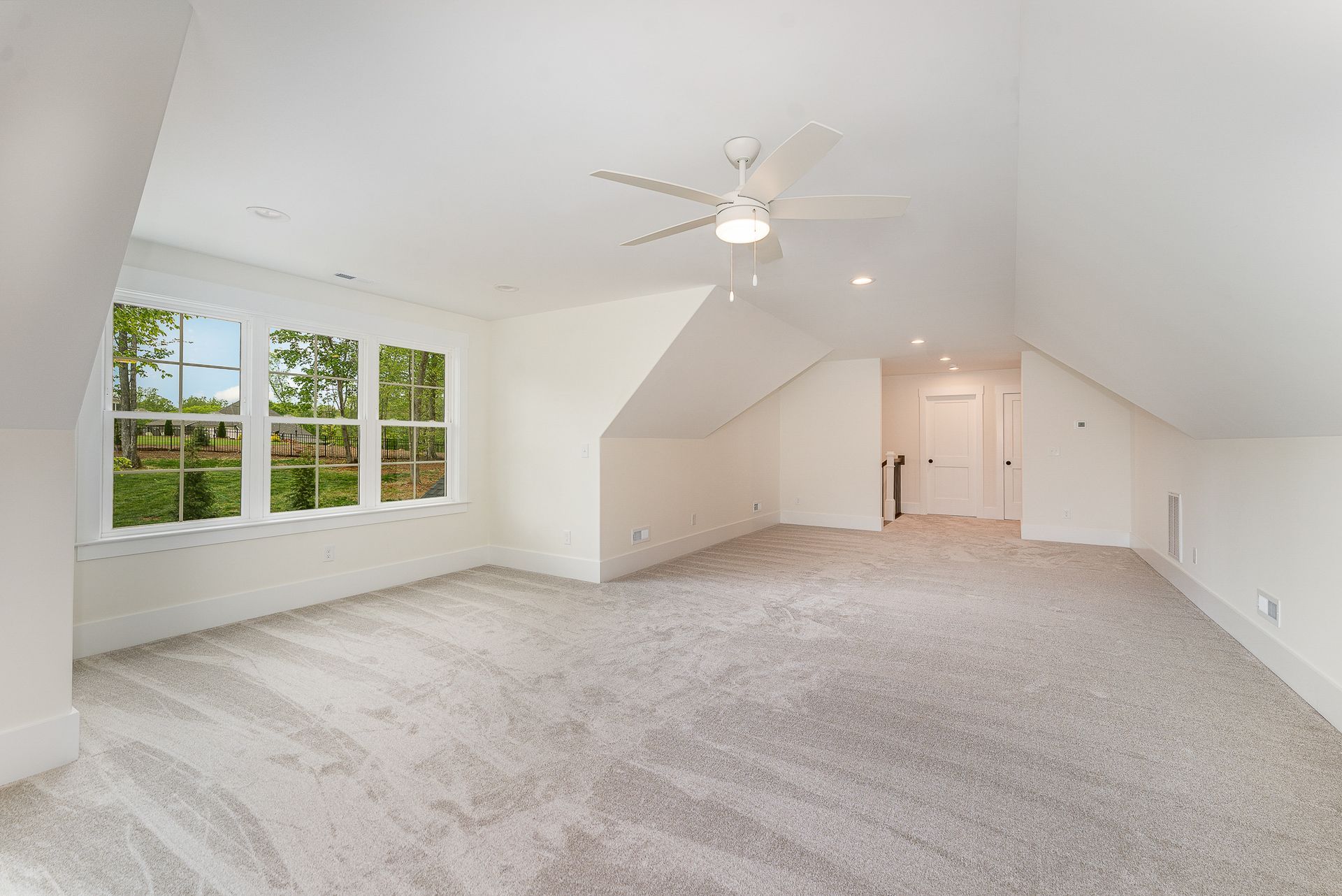 Huge empty room with a ceiling fan and a lot of windows