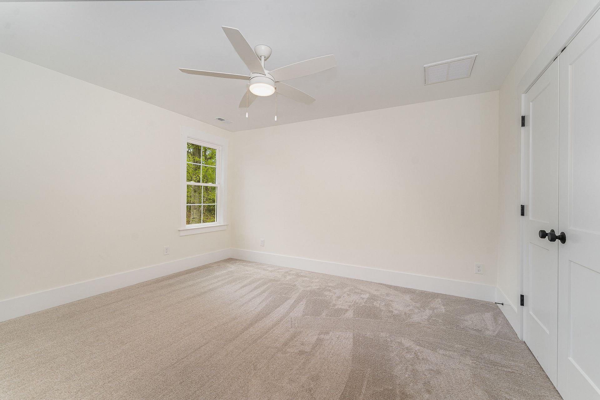 An empty bedroom with white walls and a ceiling fan