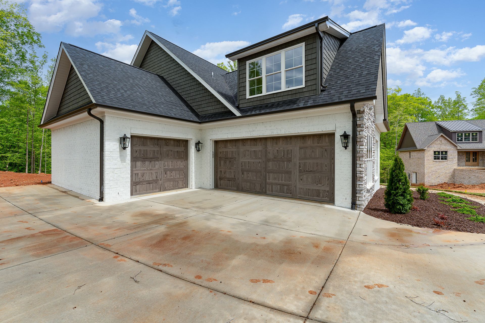 A white house with two garage doors and a black roof