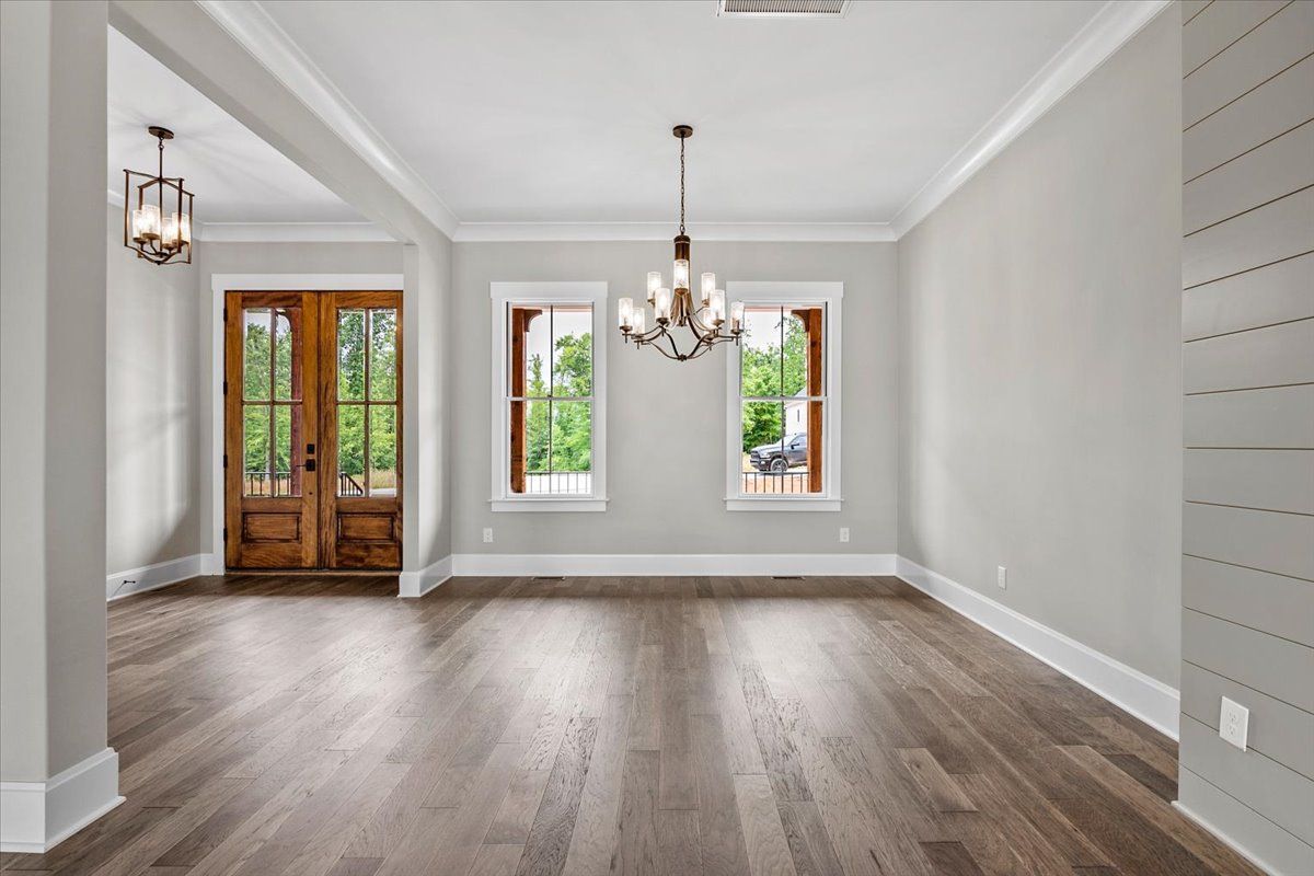 An empty living room with hardwood floors and a chandelier