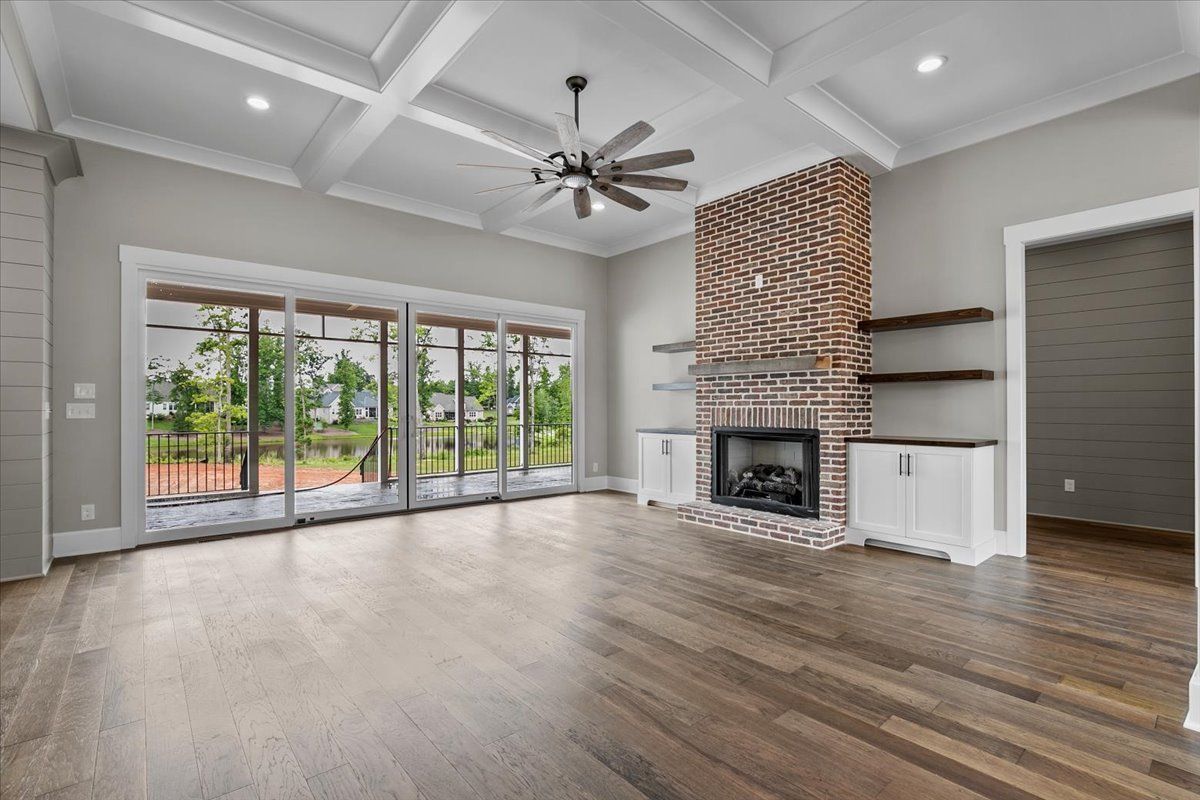 An empty living room with a fireplace and a ceiling fan