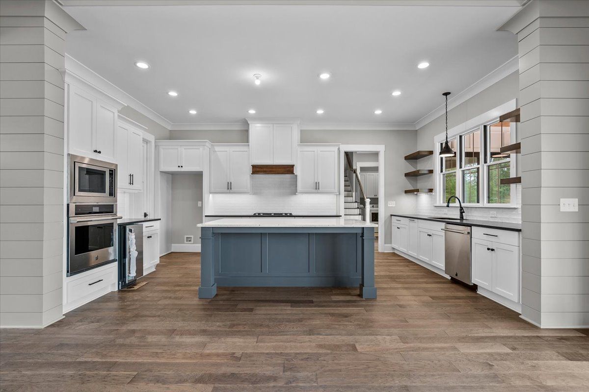A large kitchen with white cabinets and a blue island