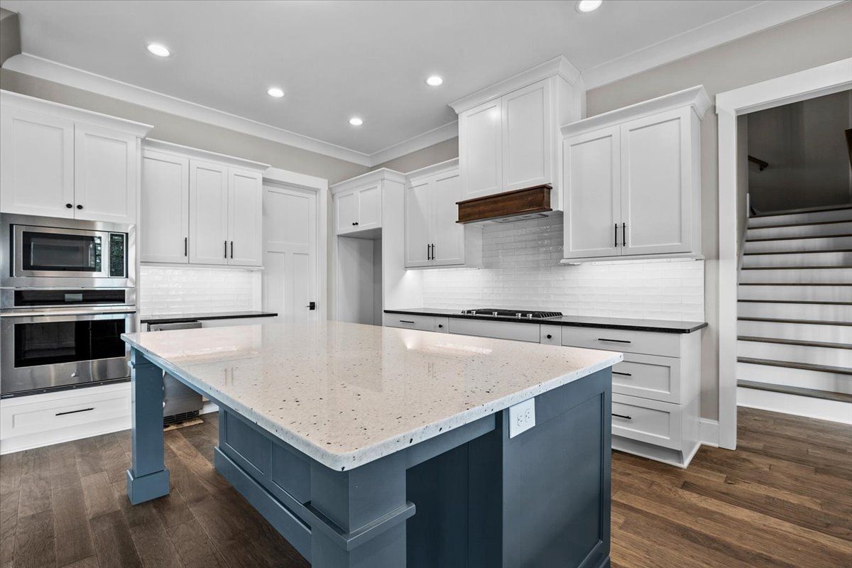 A kitchen with white cabinets, stainless steel appliances, and a large island