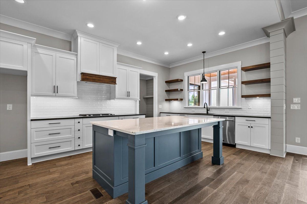 A kitchen with white cabinets and a blue island in the middle