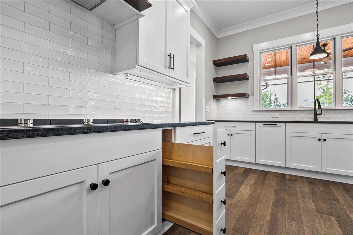 A kitchen with white cabinets and a pull-out spice rack