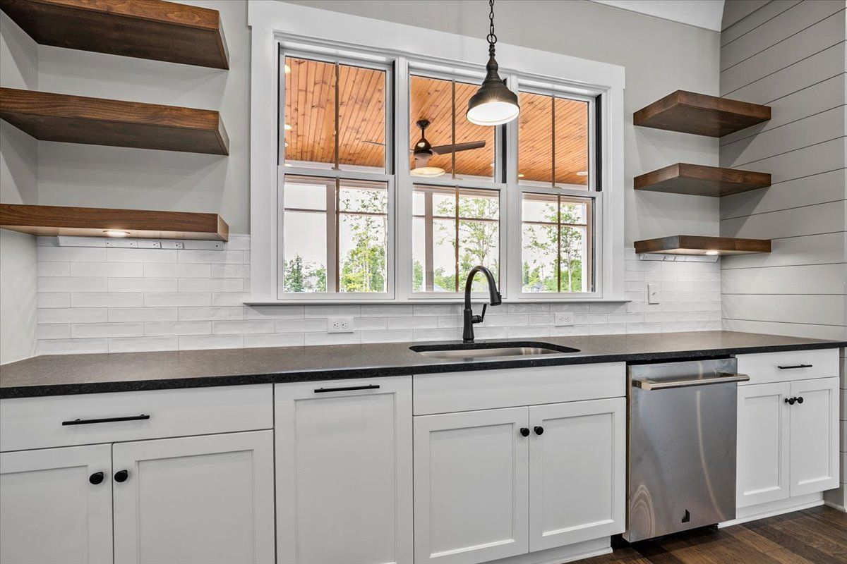 A kitchen with white cabinets and wooden shelves