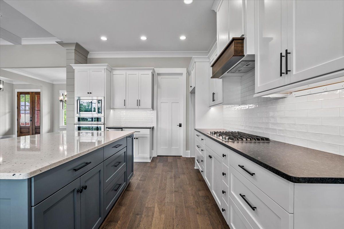 A kitchen with white cabinets, black countertops, and a large island