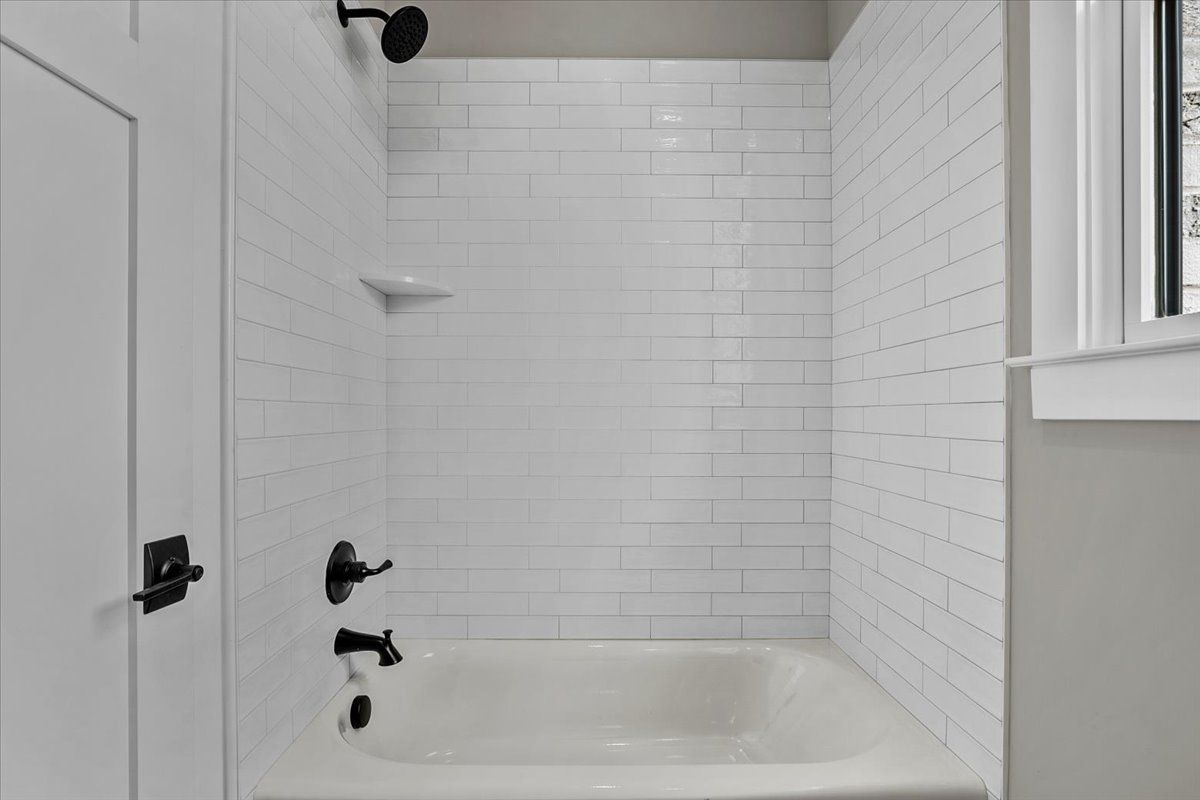 A bathroom with white tile walls and a bathtub