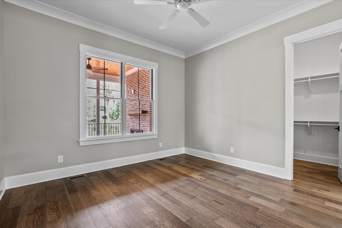 An empty bedroom with hardwood floors and a ceiling fan