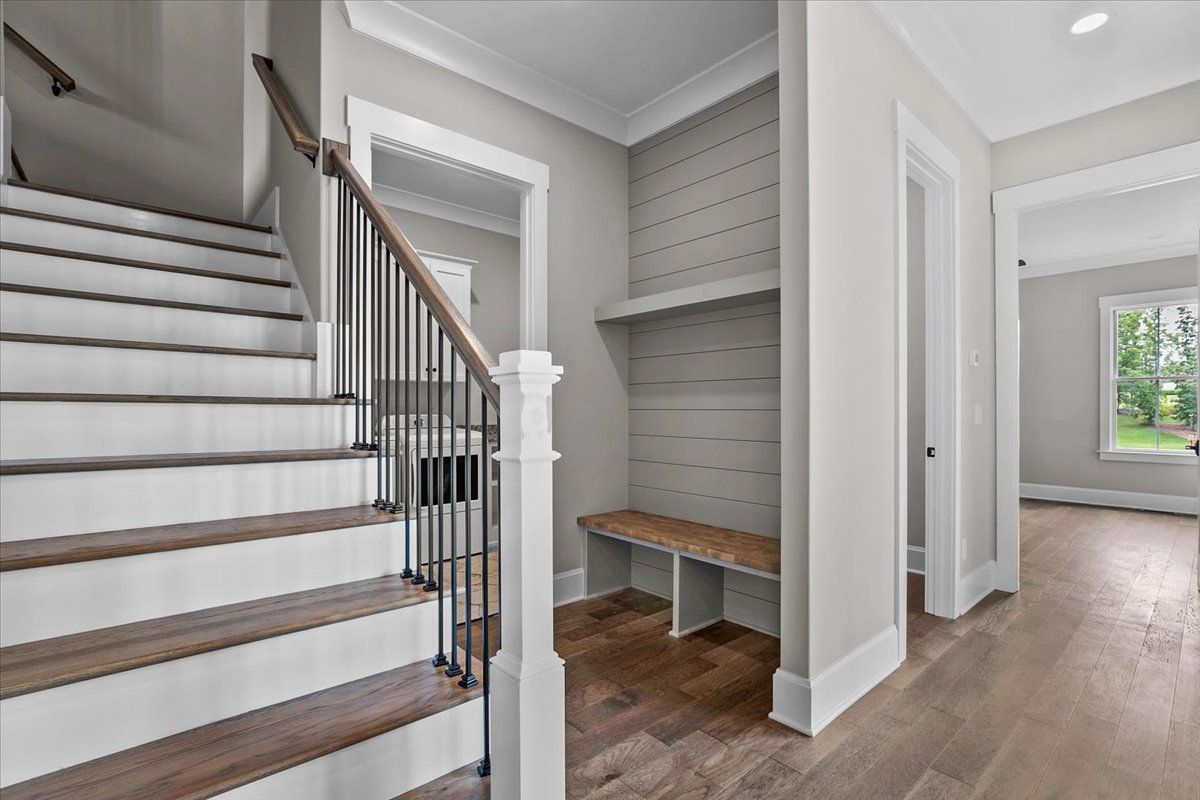 A hallway with stairs and a bench